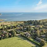 Häuser in einer grünen Landschaft mit Blick auf das Meer und einen Fluss.