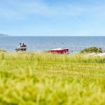 Zwei Personen sitzen auf einer Bank am Strand. Im Hintergrund ist das Meer und eine rote Bootskiste zu sehen.