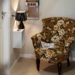 Florales Sessel mit Zeitschrift, schwarze Lampe und Wandhalterung im Flur.