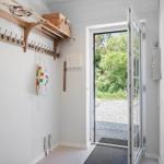 Eingangsbereich mit Hakenwand, Korb und Tür zum Außenbereich.