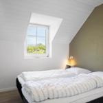 Schlafzimmer mit Dachfenster, Bett und Nachttisch.