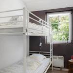 Zimmer mit Doppelstockbett, Fenster mit Blick auf Bäume und kleiner Tisch.