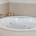 Eine runde Whirlpool-Badewanne mit Armaturen und Kerzen auf der Wand.
