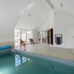 Indirekter Poolbereich mit Whirlpool und Sitzgelegenheit. Helle, geräumige Umgebung mit Fensterfront.