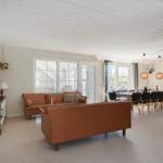 Wohn- und Essbereich mit braunen Sofas, Tisch und Stühlen. Weiße Decke und Fenster.