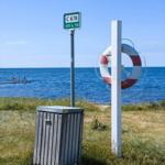 Strandufer mit Rettungsring, Mülltonne und Wegweiser C 678.