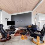 Living room with sofa, two black recliners, and fireplace. Kitchen is visible in the background.