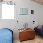 Room with two beds, nightstand, fan, and window with curtain.