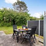 Terrace with table and chairs, surrounded by green garden and wooden fence.