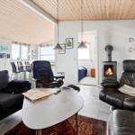 Living room with sofa, two leather chairs, and fireplace. Corridor to bedroom.