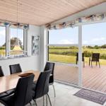 Dining area with table, chairs, and view of terrace and landscape.