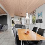 Dining area with wooden table and black chairs. Kitchen and living area are visible.