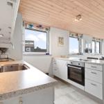 Kitchen with worktop, stove, and windows with view.