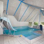 Innere Schwimmhalle mit Rutsche, Pool und Sitzgelegenheiten.