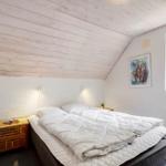 Schlafzimmer mit Doppelbett, Holzdecke und Fenster zur Natur.