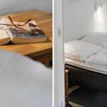 Schlafzimmer mit weißer Bettwäsche und Wandlampe. Tisch mit Buch und Brille.
