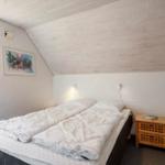 Schlafzimmer mit Dachschräge, Bett, Nachttisch und Fenster.