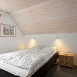 Schlafzimmer mit Bett, Nachttisch und Fenster. Holzdecke und Wandbild.
