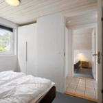 Schlafzimmer mit Bett, Kleiderschrank und Fenster. Durchgang zu weiterem Raum mit Bett.