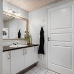 Badezimmer mit Waschmaschine, Spiegel und Duschvorhang mit Muschelmuster.