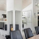 Küche mit Kühlschrank, Esstisch mit Stühlen und Kamin im Wohnbereich.