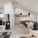 Großer Raum mit Essbereich, Kamin und Küche unter Holzdecke.
