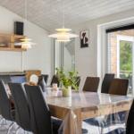 Esszimmer mit Holztisch, schwarzen Stühlen und Glasfront zur Terrasse.