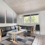 Wohnzimmer mit Sofa, Tisch und Fenster. Decke aus Holz, Wandbilder und Teppich.