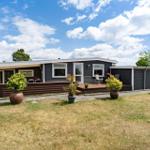 Ein modernes Haus mit Terrasse, Garten und Pflanzen unter blauem Himmel.