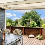Terrasse mit Tisch, Stühlen und Blick auf Spielplatz und Garten.