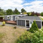 Moderne Villa mit Terrasse und Garten. Haus hat graue Fassade und weiße Fenster.