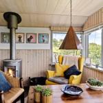 Room with fireplace, yellow armchair, and large window with view of the landscape.