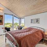 Bedroom with bed, windows, and wooden ceiling. View of the landscape.