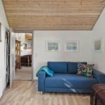 A room with a blue sofa, wooden floor, and wooden ceiling. Pictures hang on the wall.
