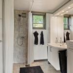 Bathroom with shower, sink, and mirror cabinet. Window with blinds and towels.