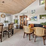 Dining area with table and chairs, living area with sofa and armchairs, wooden ceiling and wall art.