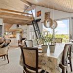Dining room with table, chairs, and view of garden. Wooden ceiling and ladder to upper level.