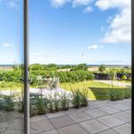 Through the glass door, you see a terrace with garden and view of the sea.