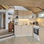Kitchen with wooden ceiling, light cabinets, and white appliances. Passage to the bathtub.