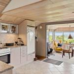 Kitchen with view of living area featuring yellow seating and wooden ceiling.