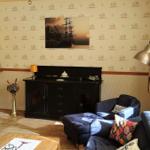 Wohnzimmer mit Sofa, Schrank und Wandtapete mit Schiffsmotiven.