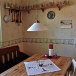 Esszimmer mit Holztisch, Bänken und Wandregalen mit Küchenutensilien.