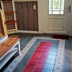 Eingangsbereich mit Holztreppe, Tür und gefliestem Boden mit Muster.