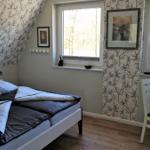Schlafzimmer mit Bett, Fenstern und Tapete mit Baum-Motiv.