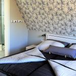 Schlafzimmer mit Doppelbett, Wand mit Baum-Motiv und angrenzender Dusche.