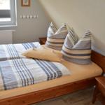Schlafzimmer mit Doppelbett, Holzrahmen, Kissen und Fenster.