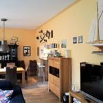 Wohn- und Essbereich mit Holzmöbeln, Wanddekoration und Fernseher.