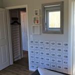Schlafzimmer mit Kleiderschrank, Spiegelschrank und angrenzendem Bad mit Waschbecken.