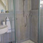 Badezimmer mit Dusche, Waschbecken und Spiegel.