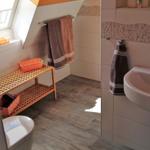 Badezimmer mit Dachschrägen, Toilette, Waschbecken und Holzregal.